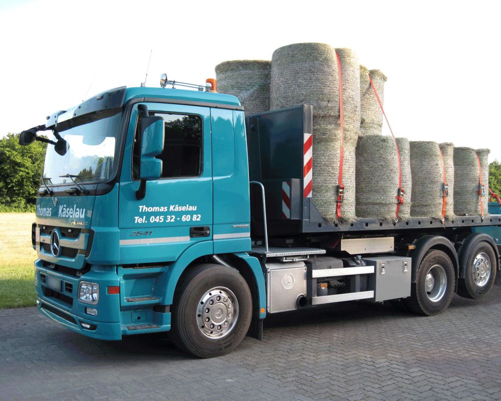 LKW von Containerdienst Thomas Käselau beladen mit Heu-Rundballen auf dem Plateaucontainer – Maschinentransport und Schwertransport in Schleswig-Holstein